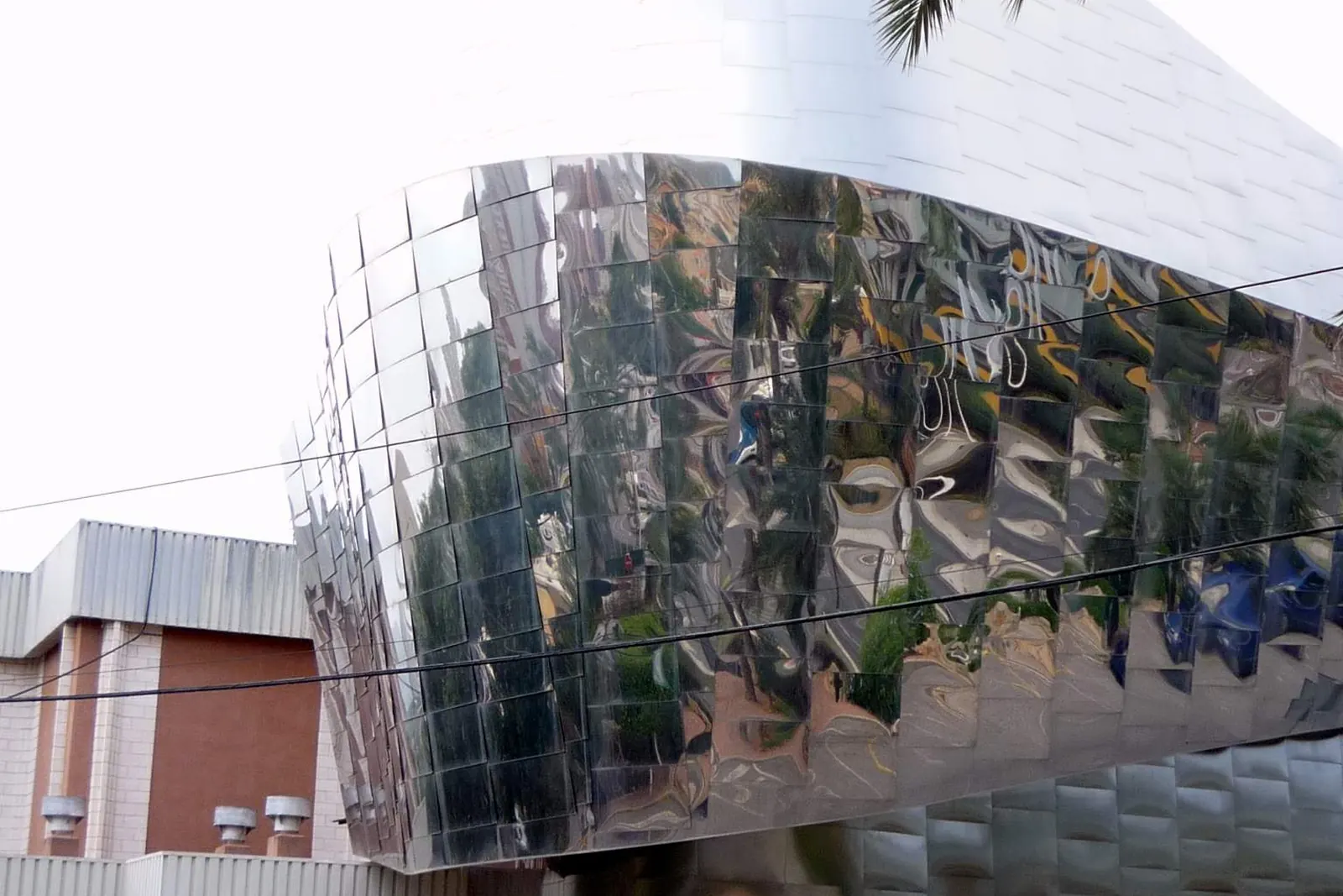 Reflections of palms and buildings in the polished metal of Benidorm Palace's curved wall